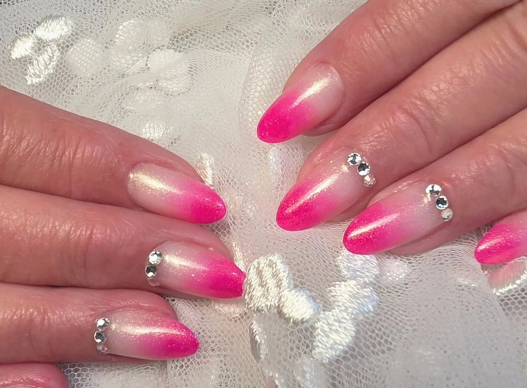 Amandelvormige nagels met een overloop van nude naar fuchsia en een steentje op elke nagel