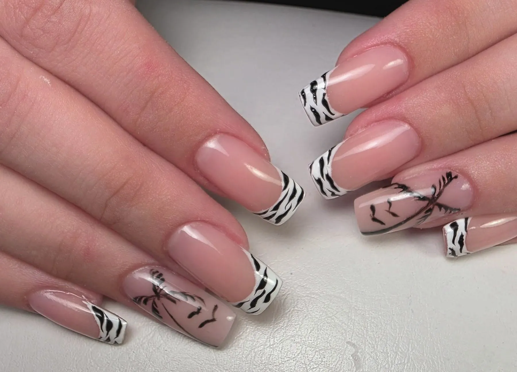Nude nagels met zwart-witte zebratips en een getekende palmboom