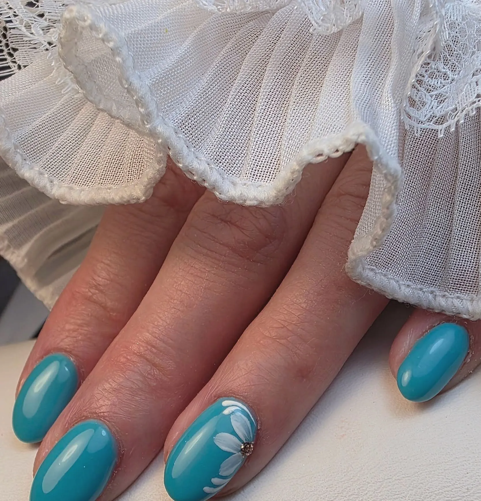 Turquoise ovale nagels met één getekend wit madeliefje