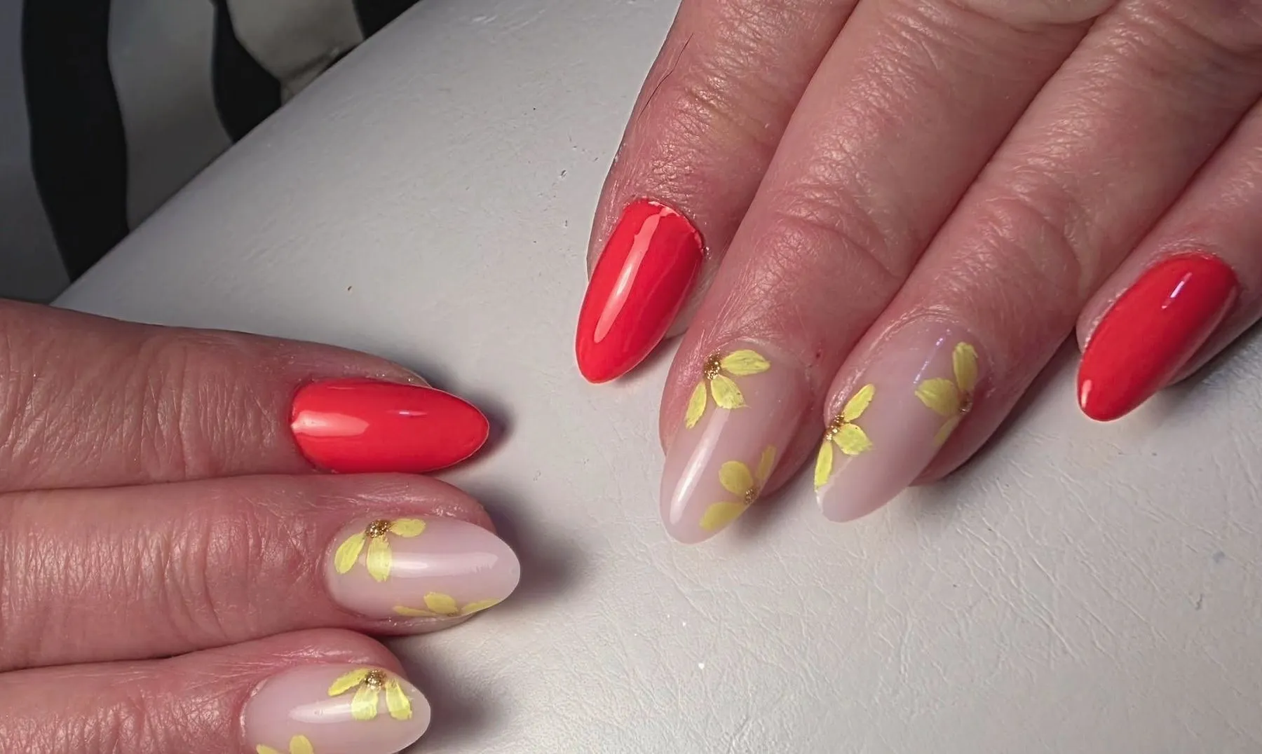 Koraalrode nagels en nude nagels met getekende gele bloemetjes