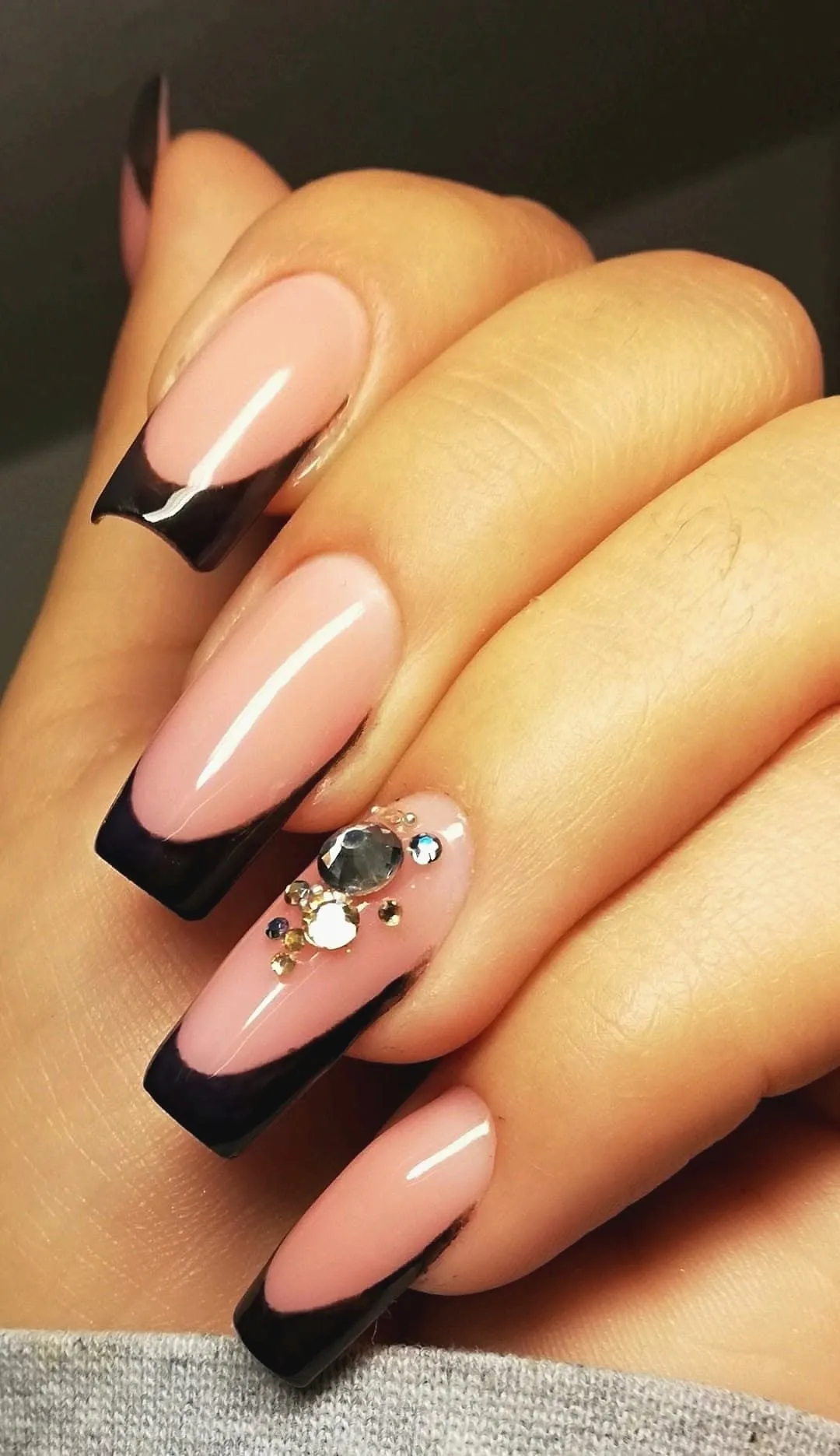 Lange coffin-nagels met zwarte french tips en steentjes op één nagel